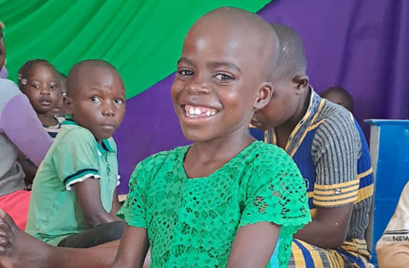 A smiling girl in Kenya wearing a green shirt